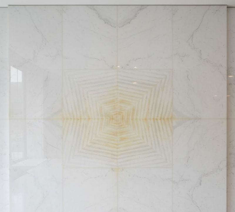 Yellow discoloration pattern on white marble wall tiles.