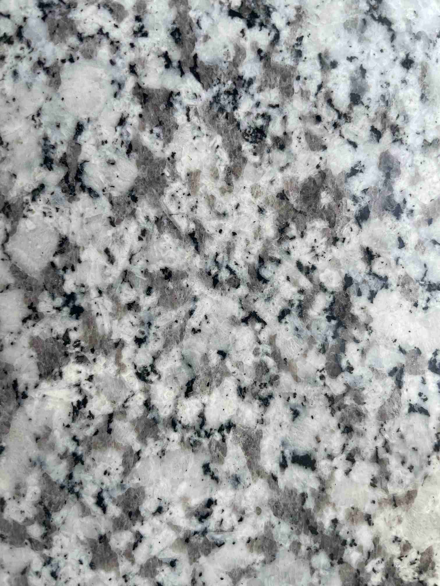 Close-up of flamed Jilin White granite showing a light grey crystalline texture for outdoor paving.