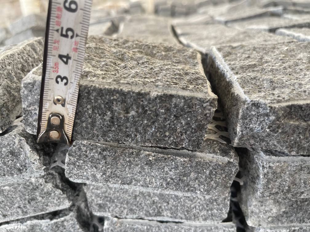 Granite setts with natural-split top and side faces and a sawn bottom for controlled bedding.